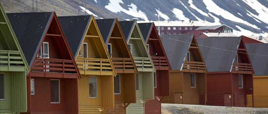 Kleurige houten huizen in Barentsburg, Spitsbergen, met bergen op de achtergrond.