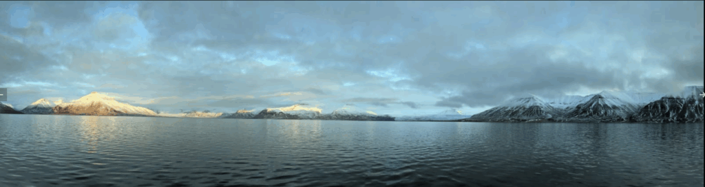 Panoramisch uitzicht op bergen bedekt met sneeuw en een rustig wateroppervlak in Spitsbergen.